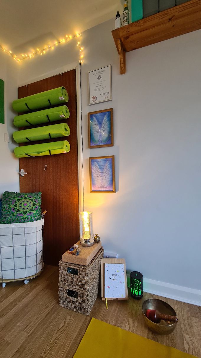 a yoga room with a wooden floor, with yoga mats, blankets, cushions and a singing bowl